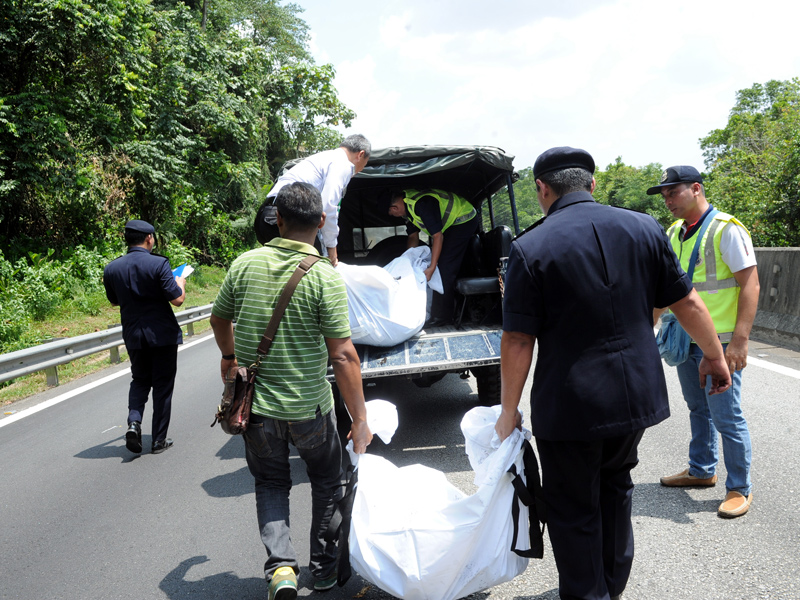 Anggota polis mengangkat mayat yang ditemui di bawah treler untuk dibawa ke Hospital Raja Permaisuri Bainun Ipoh. - Foto BERNAMA
