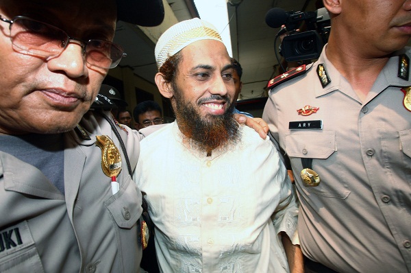 FILE - In this Nov. 29, 2011 file photo, terrorist suspect Umar Patek, center, is escorted by police officers as he arrives to testify for his wife, Ruqayyah binti Husein Luceno, who is on trial for immigration violations, at a district court in Jakarta, Indonesia. Southeast Asia's most notorious suspected bombmaker, nicknamed the "Demolition Man," is facing trial in Indonesia for his alleged role in the 2002 Bali bombing. Umar Patek's trial begins Monday, Feb. 13, 2012, in a Jakarta court. It follows his nine-year flight from justice that took him from the Philippines to Pakistan. (AP Photo/Tatan Syuflana, File)